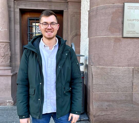 Zu sehen ist der Student Timo Lind vor dem Eingang der PH Heidelberg.