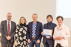 Auf dem Bild sieht man wie Johannes Wegenkittl den Uwe-Uffelmann-Preis 2019 in den Händen hält, er ist umgeben von vier weiteren Personen.
