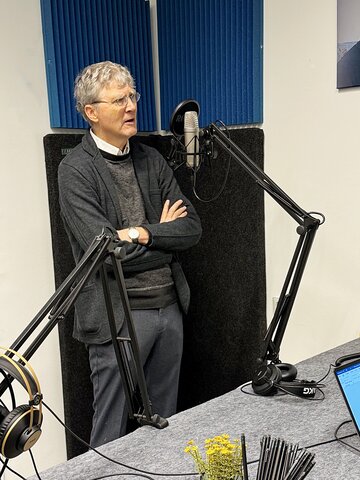 Zu sehen ist Prof. Mehring am Mikrofon im Podcast-Studio.
