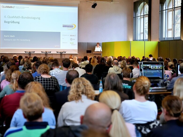 Blick auf das QuaMath-Podium in der Festhalle der Pädagogischen Hochschule Heidelberg. Vorne sieht man Rektorin Karin Vach am Rednerpult. 