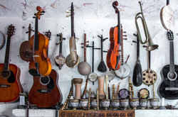 Das Foto zeigt verschiedene Streichinstrumente die an der Wand hängen in der Musikwerkstatt.