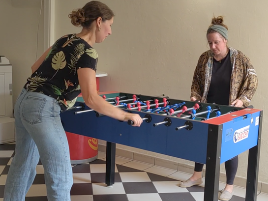 Zwei Studentinnen spielen Tischkicker im Altbau der Pädagogischen Hochschule Heidelberg und sind so durch PHeelGood körperlich bewegt.