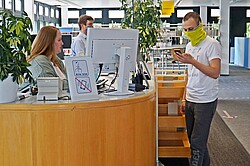 Auf dem Bild sieht man einen Studierenden mit Maske bei der Studienanmeldung.