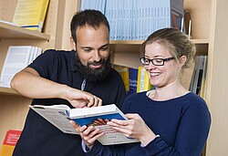 Mann der einer Frau etwas in einem Buch zeigt.