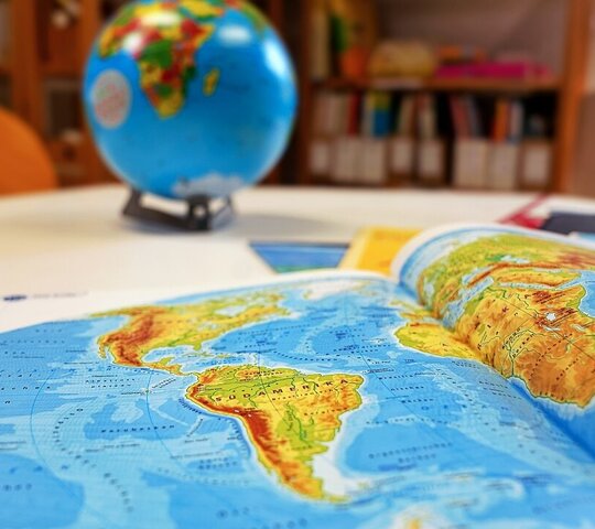 Eine Karte der Welt auf einem Tisch mit einem Globus im Hintergrund.