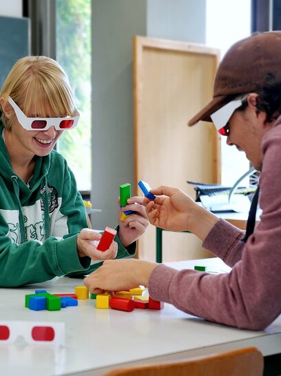 Studierende der Physik experimentieren mit Holzklötzen und roten Brillen  
