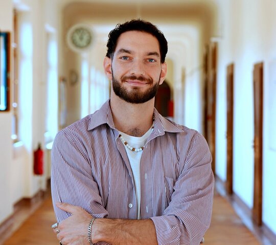 Porträtfoto von Tim Rossatti im Flur des Altbaus der Pädagogischen Hochschule Heidelberg.
