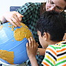 Das Foto zeigt eine Frau die einem Jungen etwas auf einem Globus zeigt.