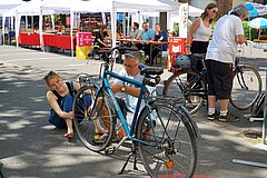 Person repariert Fahrrad, andere Person schaut zu