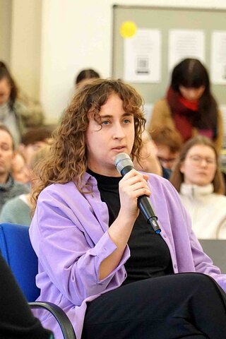 Zu sehen sind zwei Studierende, die an einer Diskussionsrunde teilnehmen.