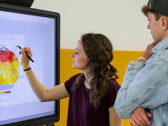 Das Foto zeigt zwei Personen an einer digitalen Tafel.