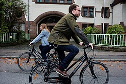 zwei Fahrradfahrer vor dem Haupteingang des Altbaues der Pädagogischen Hochschule. Copyright Pädagogische Hochschule Heidelberg