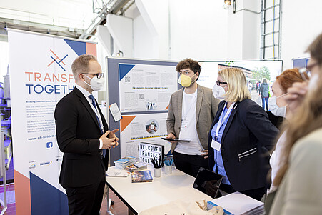 Vier Menschen diskutieren an einem Messestand.