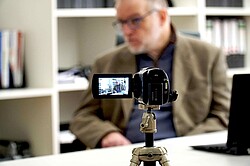 Das Bild zeigt Hartmut Kabelitz im Hintergrund. Im Vordergrund ist eine Stativ mit einer Kamera aufgebaut. Copyright Pädagogische Hochschule Heidelberg