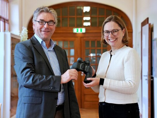 Das Foto zeigt die symbolische Übergabe eines Fernglasses zwischen Friesen und Siegmund.