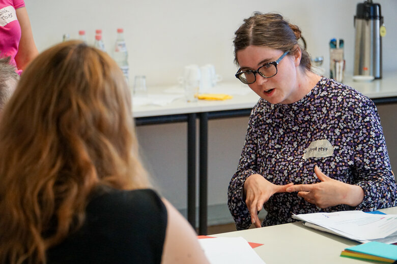Das Bild zeigt Anna Neff im Gespräch mit einer Person während eines Workshops.