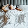 Eine Frau liegt mit Schlafmaske im Bett