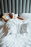 Eine Frau liegt mit Schlafmaske im Bett