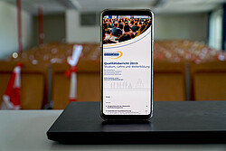 Das Symbolbild zeigt ein Smartphone, auf dem der Qualitätsbericht geöffnet ist. Copyright Pädagogische Hochschule Heidelberg.