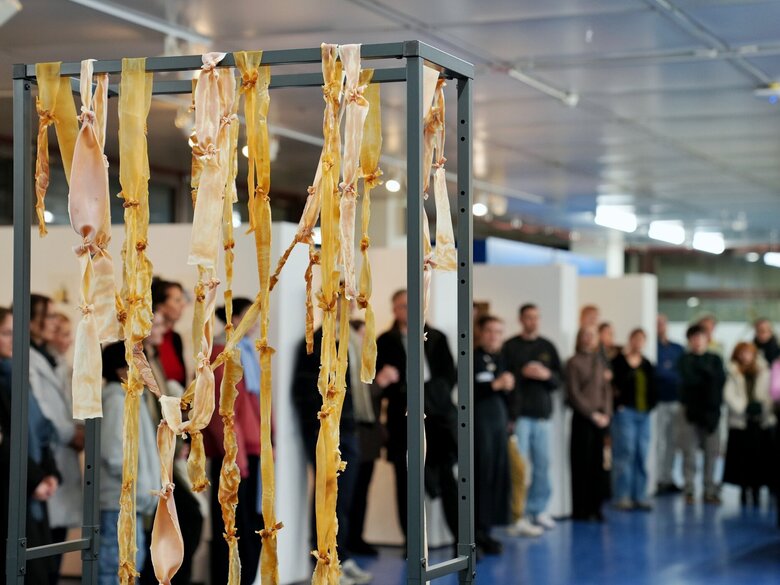 Zu sehen ist eine Plastik und im Hintergrund das Publikum 