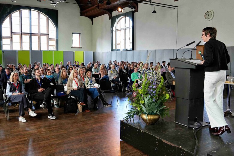 Werden Sie Mitglied in der Graduate School und Sie können an tollen Veranstaltungen teilnehmen, wie hier auf diesem Bild zu sehen in der Festhallte der PH Heidelebrg. Die Retkoratin Frau Vach steht vorne auf einem Podium und hält eine Rede vor einer vollbesetzten Halle.