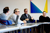 Das Foto zeigt unterschiedliche Menschen an Tischen im Senatssaal der PH Heidelberg sitzen.