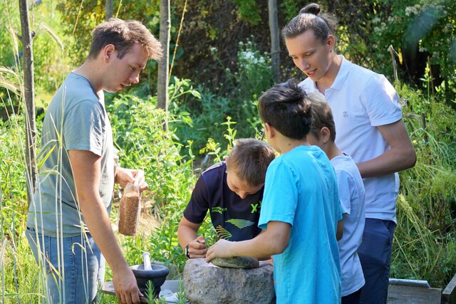 Zwei Studenten stehen im Ökogarten der Pädagogischen Hochschule Heidelberg. Sie beobachten drei Schüler, die etwas bauen. Ein Beispiel für nachhaltige Lehre.  