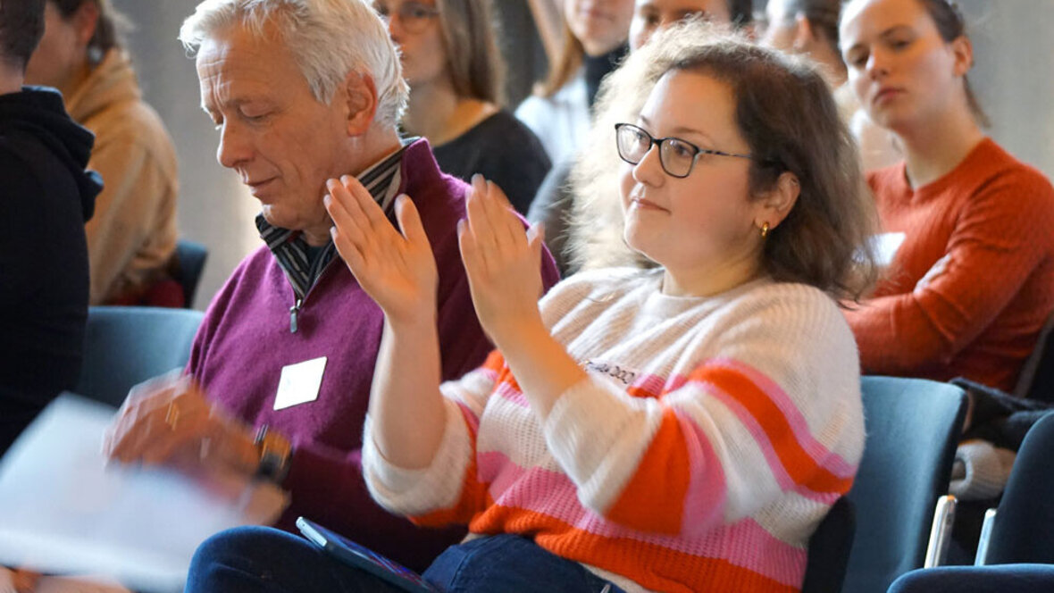 Eine Frau im Publikum; sie klatscht mit den Händen.