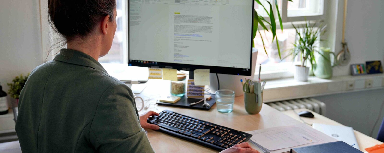 Eine Mitarbeiterin der Pädagogischen Hochschule Heidelberg steht an ihrem Stehtisch und arbeitet durch den Haltungswechsel gesund. 