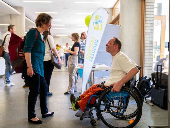 Das Bild zeigt Thorsten Lihl auf dem Landesfachtag für Quartiersentwicklung in Stuttgart. Er spricht mit einer Besucherin.
