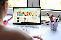 Das Foto zeigt eine Frau am Schreibtisch mit ihrem Laptop und Stiften.