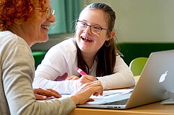 Das Foto zeigt zwei Personen, welche gemeinsam vor einem Laptop sitzen.