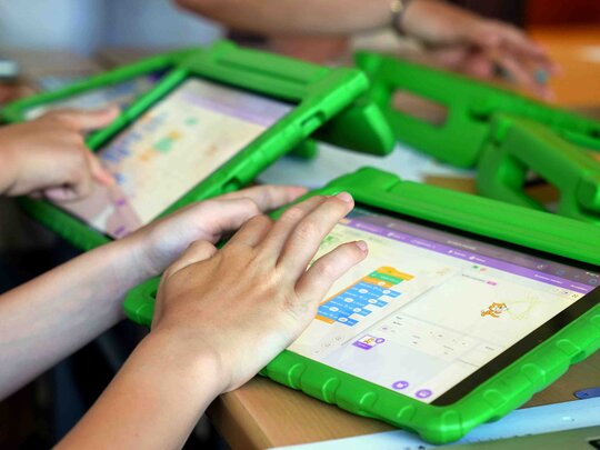 Zu sehen sind Kinderhände, die mit Tablets interagieren.