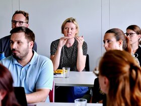 Junge Forschende aus dem Publikum diskutieren beim Nachwuchskolloquium 2026 der Fakultät III