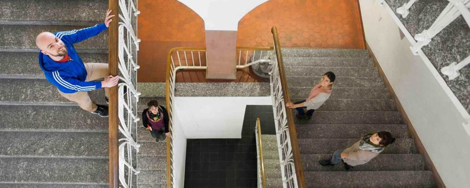 Blick von oben auf Personen im Treppenhaus.