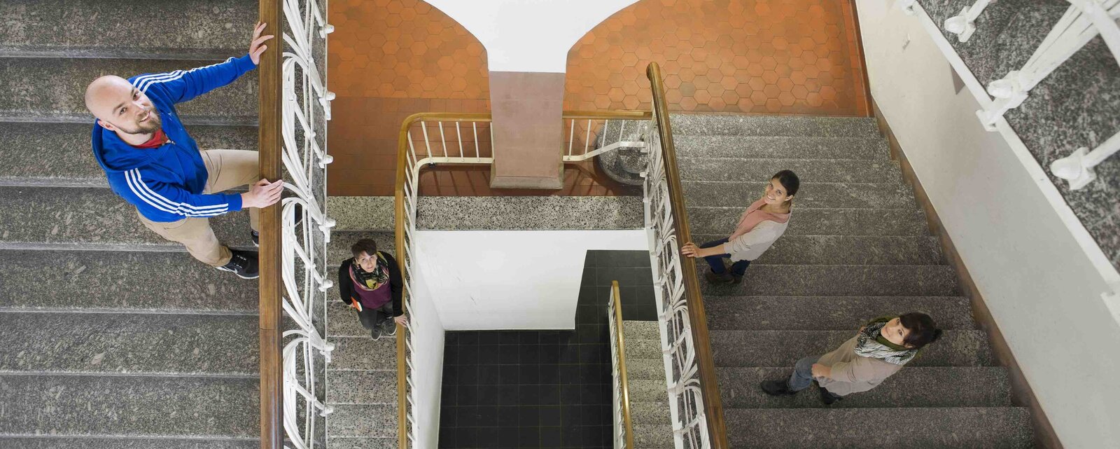 Blick von oben auf Personen im Treppenhaus.