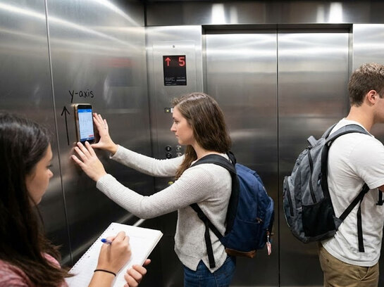 Studierende bei einem Experiment im Fahrstuhl: Mit ihrem Handy messen sie die Geschwindigkeit