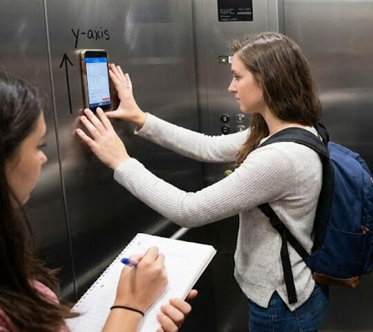Studierende bei einem Experiment im Fahrstuhl: Mit ihrem Handy messen sie die Geschwindigkeit