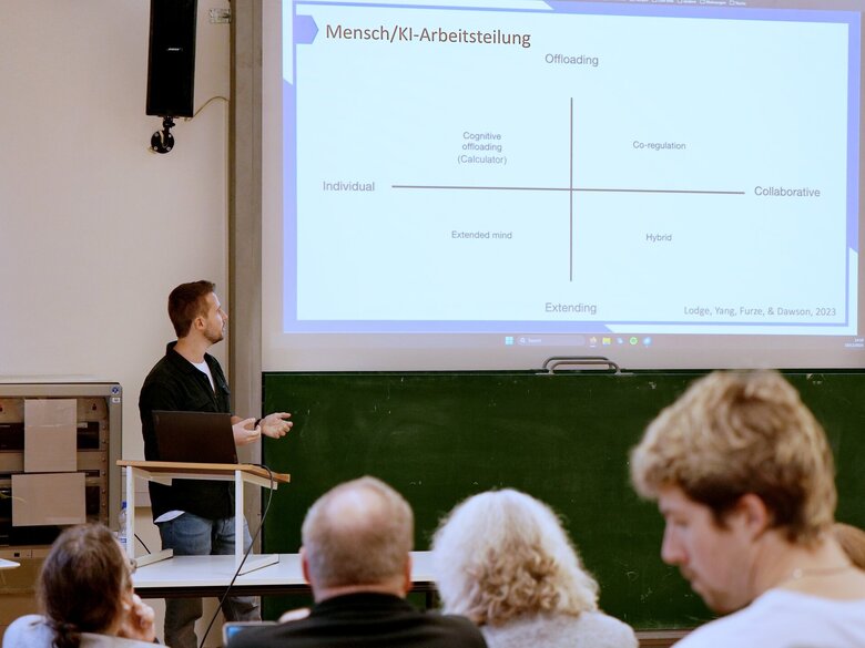 Das Foto zeigt einen Redner und Publikum beim Vortrag zu KI-Einsatz in der Lehre 
