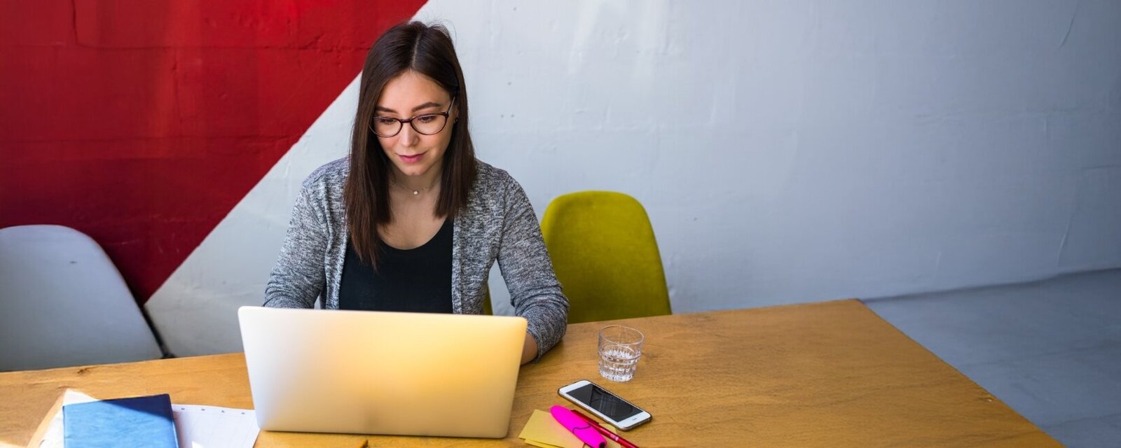 Person sitzt an ihrem Arbeitsplatz und schaut in ein Laptop