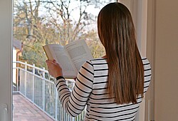 Auf dem Bild erkennt man eine Frau die ein Buch liest.