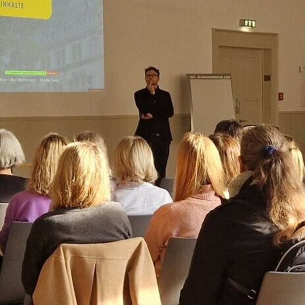 Aula der Pädagogischen Hochschule Heidelberg. Zu sehen ist ein voller Saal mit Menschen, die einem Vortrag zuhören.