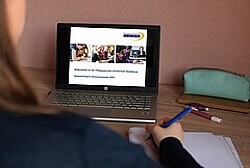 Das Bild zeigt einen Laptopbildschirm, auf dem eine Folie der PH Heidelberg zu erkennen ist. Vor dem Laptop siztz eine Person mit einem Stift in der Hand. Copyright Pädagogische Hochschule Heidelberg