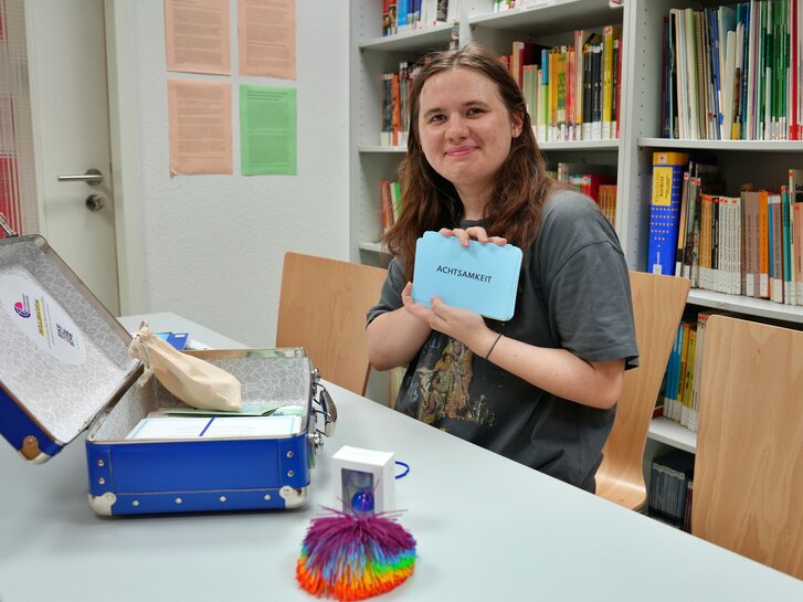 Ein Foto einer Studentin der Politikwissenschaft vor einem offenem Koffer der didaktischen Werkstatt.