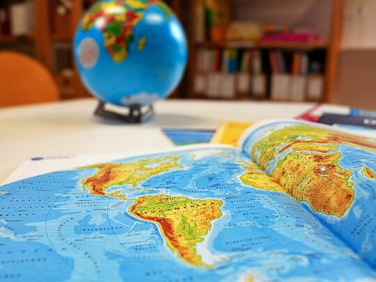 Eine Karte der Welt auf einem Tisch mit einem Globus im Hintergrund.