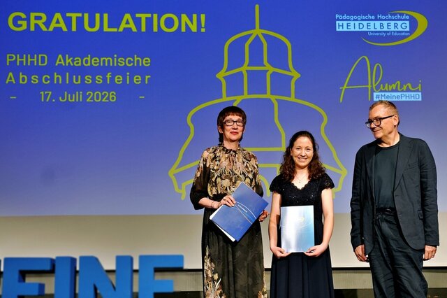 Zu sehen sind Absolvent:innen der PHHD, die sich mit ihren Urkundenmappen auf der Bühne zum Gruppenfoto aufgestellt haben.