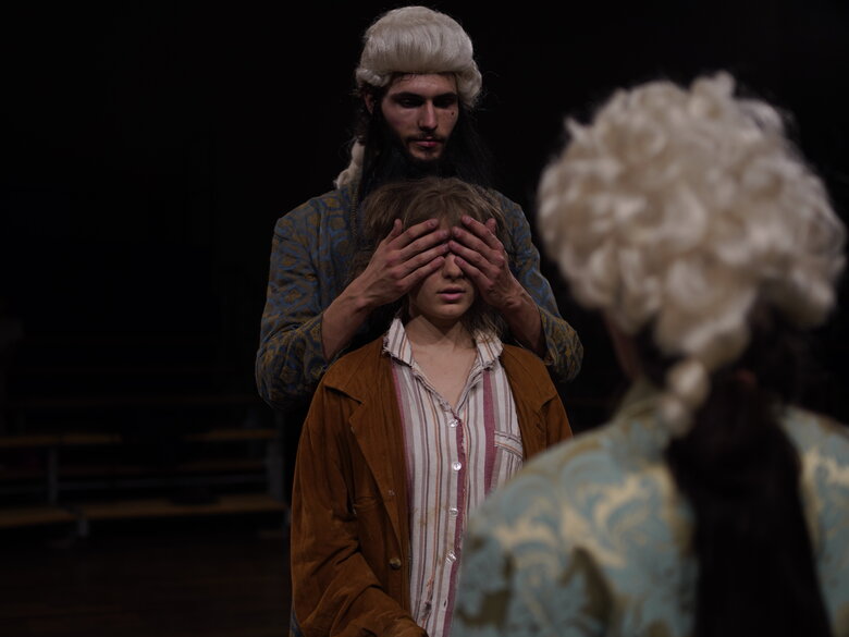 Studierende der Theaterpädagogik in einer Aufführung: Momo spricht mit Meister Hora. Der andere Meister Hora steht hinter ihr und hält ihr die Augen zu.