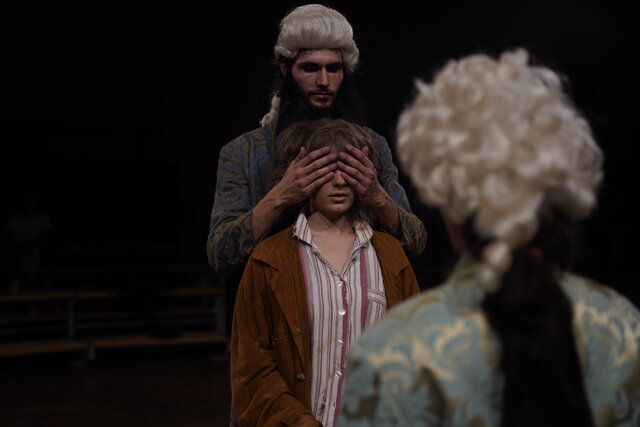 Studierende der Theaterpädagogik in einer Aufführung: Momo spricht mit Meister Hora. Der andere Meister Hora steht hinter ihr und hält ihr die Augen zu.
