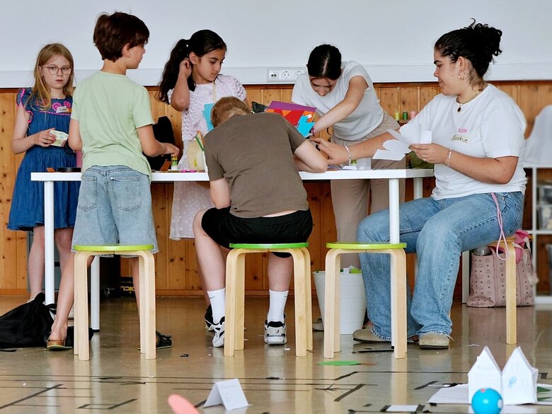 Eine Studentin arbeitete mit verschiedenen Kindern. Sie sitzen gemeinsam um einen Tisch.