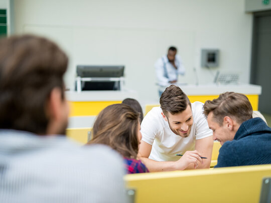 Drei Studierende planen gemeinsam im Hörsaal ihren Auslandsaufenthalt.